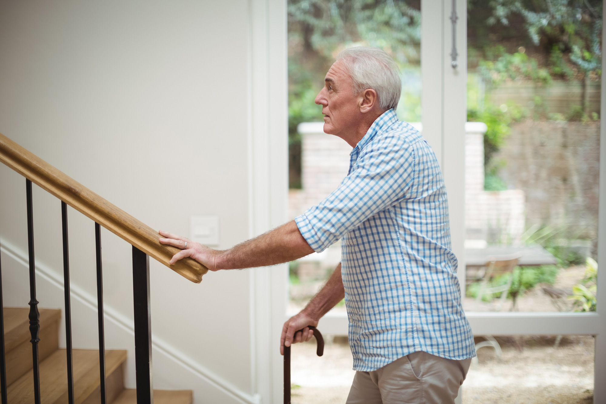 man-bottom-stairs Elderly man about to climb stairs with cane. irs